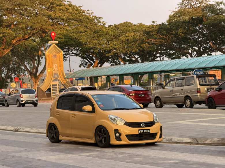 A yellow-orange Perodua 5-door supermini.