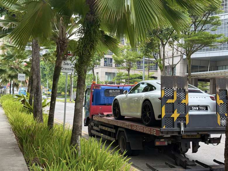 A white Porsche 911 needing a tow in Singapore.
