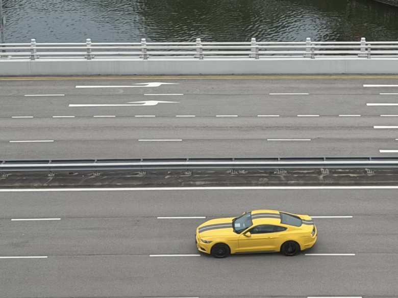 A yellow sixth-generation Ford Mustang with black racing stripes.