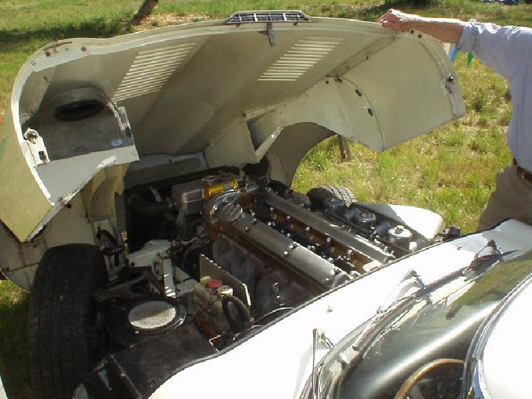 Under the bonnet of the E-type, you can see the massive inline-6 with no less than 3 SU carburetors.