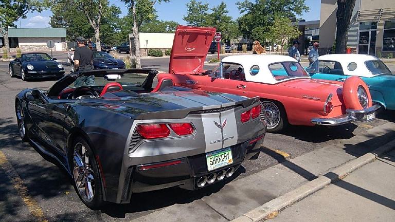 A grey seventh-generation Corvette convertible with two 1950s-era Ford Thunderbirds.