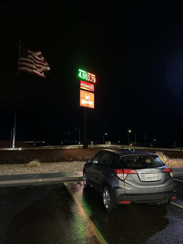 The Honda HR-V rental car at a gast station at night near the Nevada-Arizona border, with an American flag flying in the background.