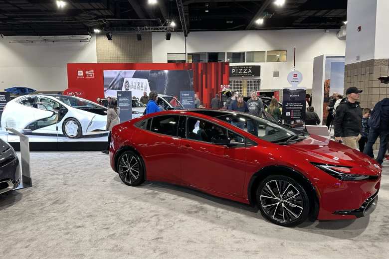 A red fifth-generation Toyota Prius, with the design concept in the background.