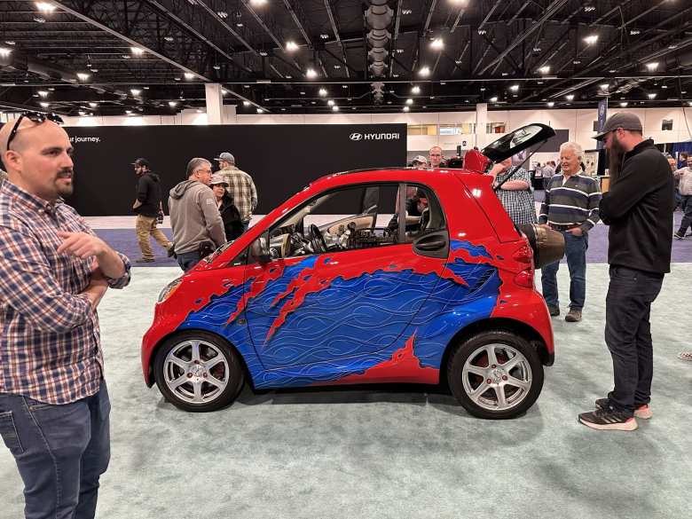A red/blue Smart car with a jet engine.