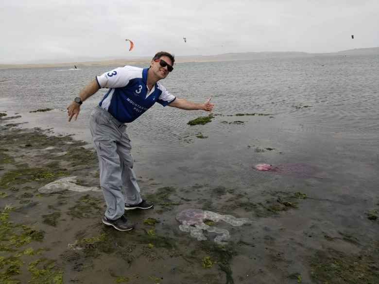 Matthew with jellyfish on the ground in paragliders in the background.