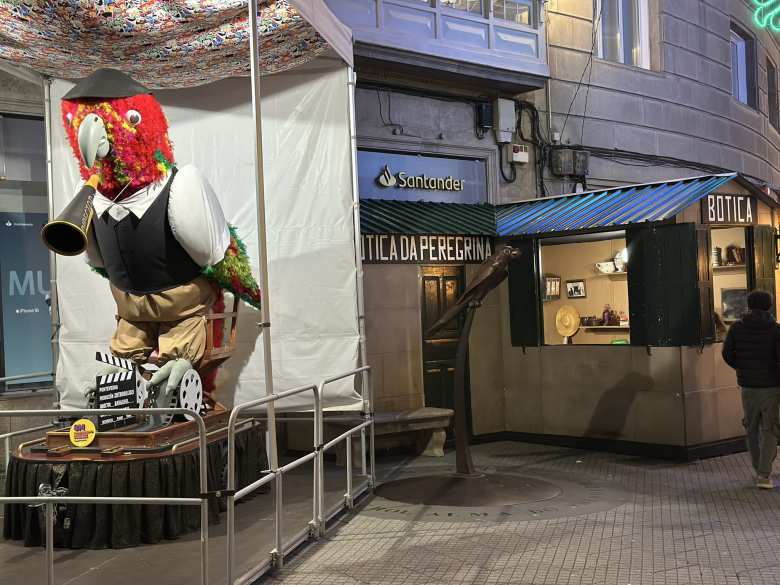 Ravachol, now dressed up in a black vest and pants, standing in the Plaza de la Peregrina next to a makeshift Botica da Peregrina. Both the botica and Ravachol existed around 1900.