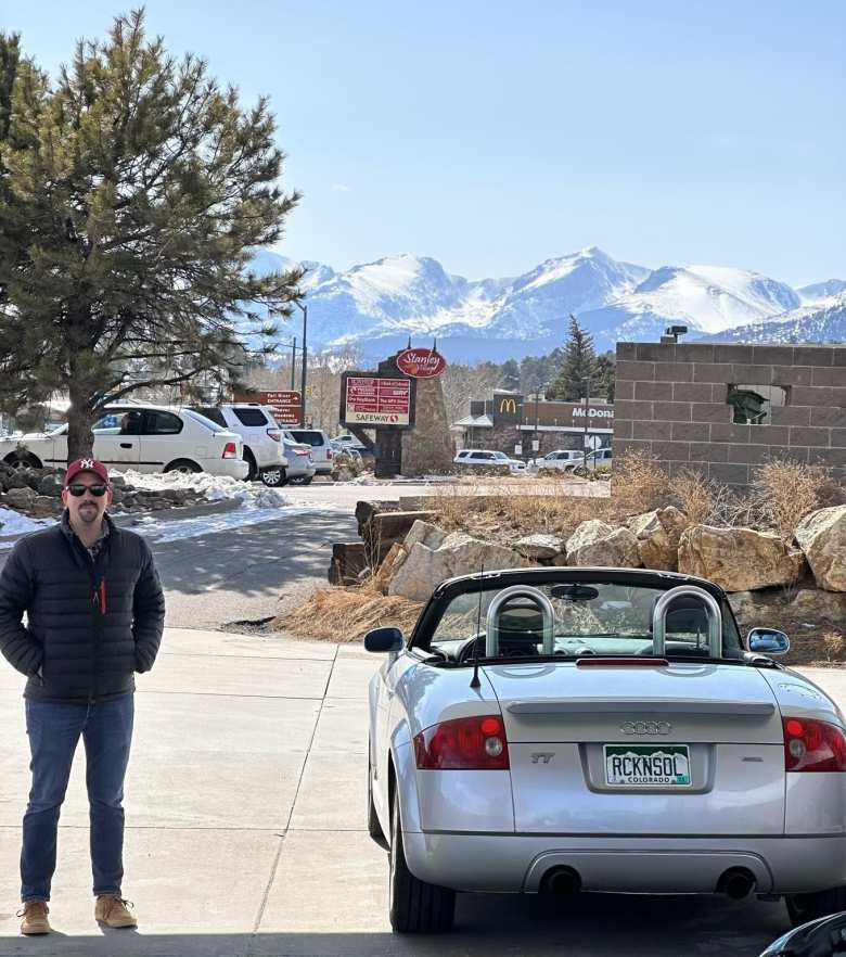Manuel with my Audi TT Roadster Quattro at a gas station in Estes Park, with the snow-covered Rocky Mountains in the background.