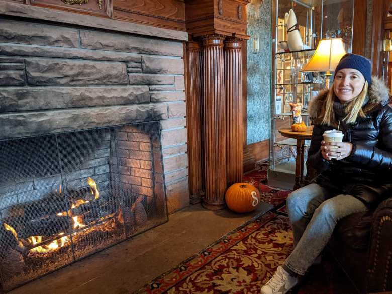 Andrea with a cup of coffee by the fireplace inside the Stanley Hotel.