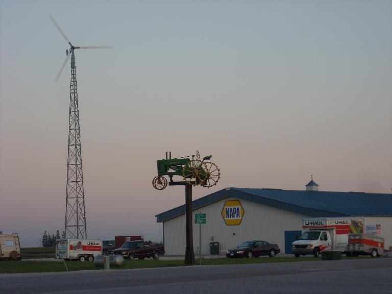 A windmill and lawn tractor by a Napa Auto Parks store not too far from Des Moines, Iowa.