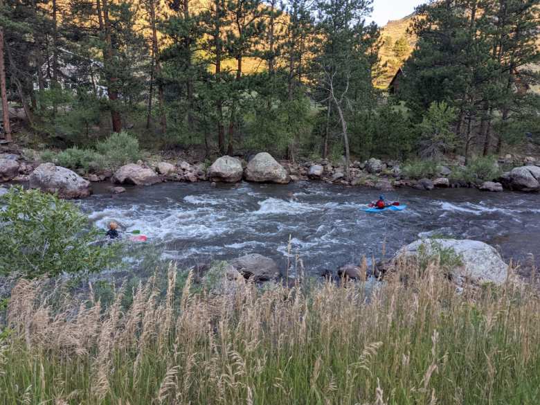 Two kayakers navigating by the Poudre River.