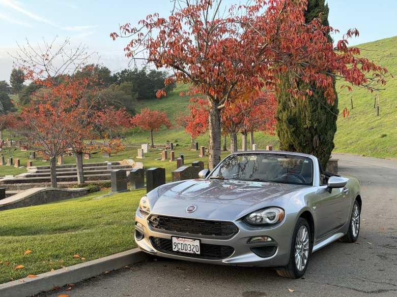Front view of the Aluminum Metallic 2017 FIAT 124 Spider Turo rental at a cemetery in Oakland, California.