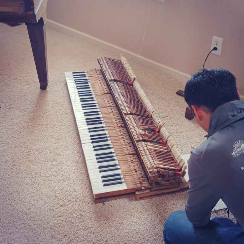 Felix Wong fixing the keyboard of a 1924 Chicago Cable Company baby grand piano.