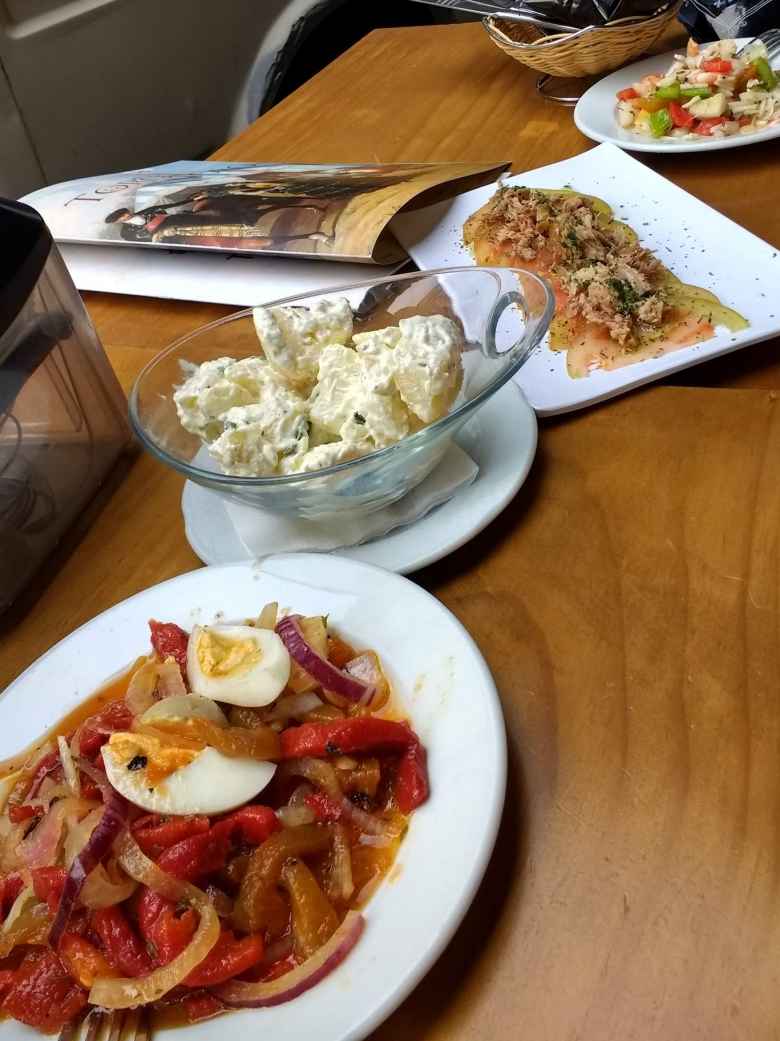 Tapas in Granada, including an egg, onion, and bell peppers dish; potato salad; shredded meat on sliced tomatoes; and shrimp with bell peppers and other sorts of vegetables.
