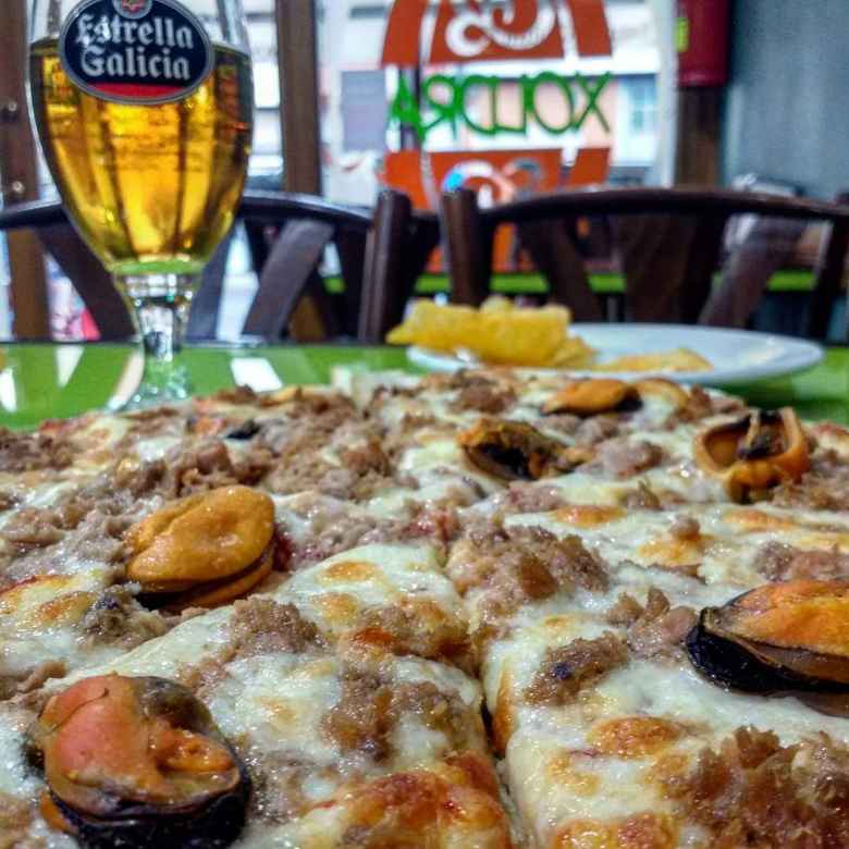 Pizza and Estrella Galicia beer at Xoldra Pizzeria in Melide, Spain.