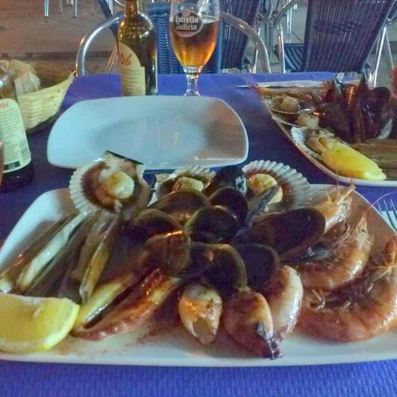 A seafood tasting menu, including grilled octopus, grilled squids, grilled pocket knife clams, big shrimps, scallops, and mussels in Fisterra, Spain.