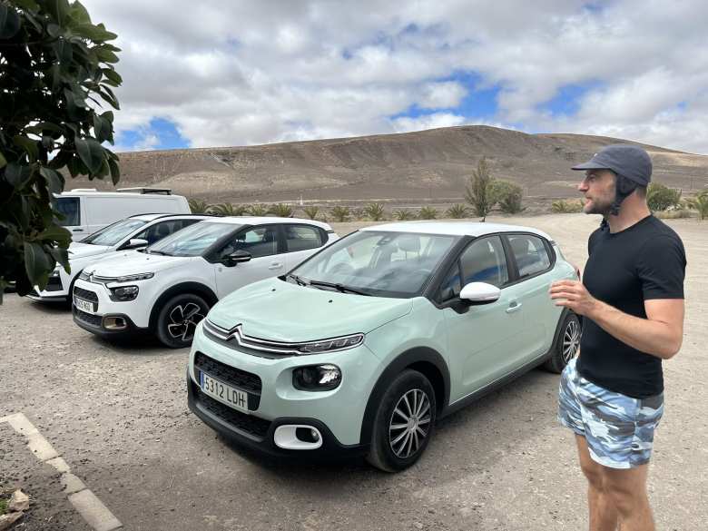 Chris with his greenish Citroën C3 rental car parked next to a similar one in white.
