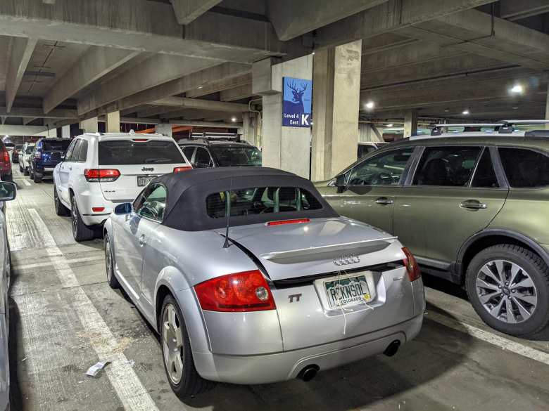 Andrea's check-in-sized suitcase fit in the Audi TT Roadster's trunk but sat slightly too high. I ran string through its latch striker and secured it to the license plate screws to keep the trunk lid closed.