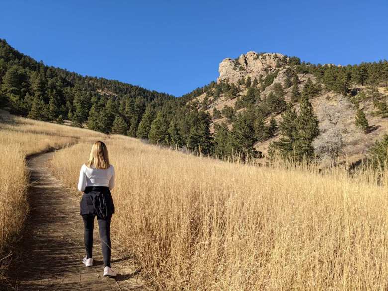 Andrea walking towards Arthur's rock in Lory State Park, surrounded by golden grasses.