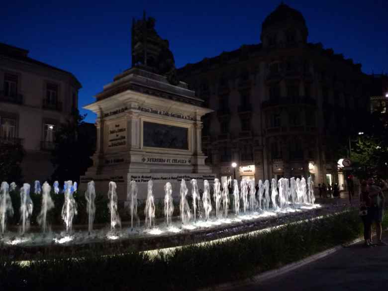 Fountain and statue at the Plaza de Isabel La Católica in Granada, Spain at night.