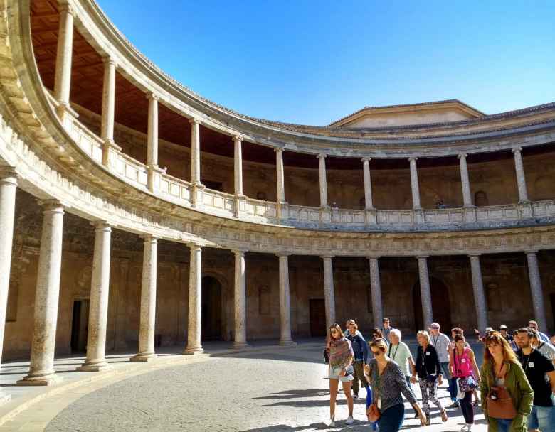 Visitors in the center of the lower level of the circular patio of the Palace of Charles V (Palacio Carlos V).