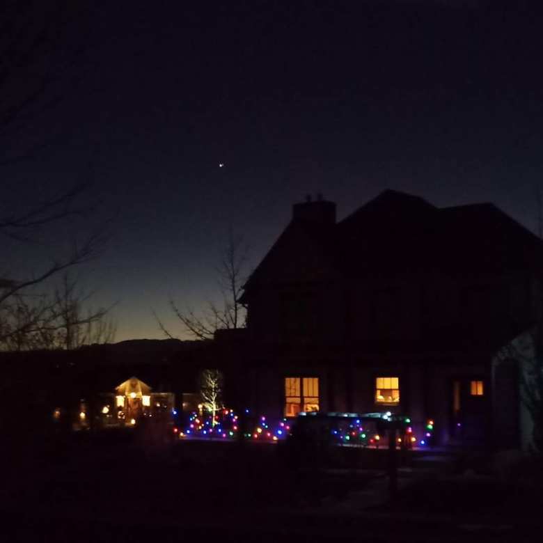 Great Conjunction of Jupiter and Saturn over two-story house decorated with Christmas lights