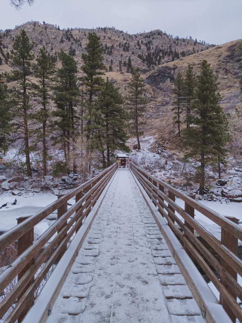 wooden bridge with snow, over the frozen Poudre River, leading to the Greyrock Trail