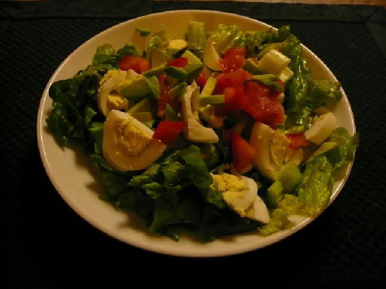 Chef salad with green lettuce, hard-boiled eggs, tomatoes, avocado, and celery.