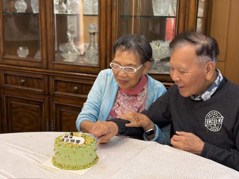 My aunt helping my dad cut a Singaporean Pana cake with pistachio cream on her birthday.