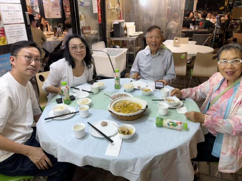 Samuel, Carlina, my dad, and aunt around a round table with a chicken stew.