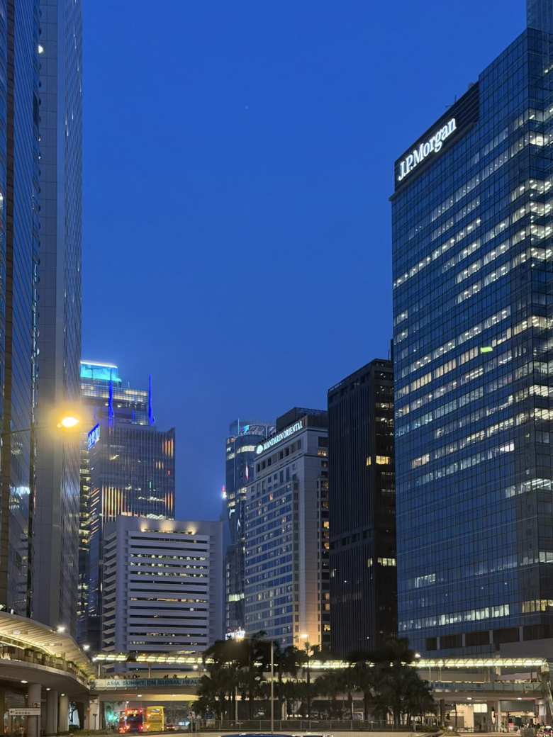 he Hong Kong skyline glows at dusk, showcasing the sleek architecture of the financial district, including the Mandarin Oriental and J.P. Morgan.