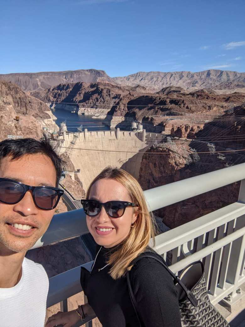 Felix and Andrea on the pedestrian side of the Mike O'Callaghan–Pat Tillman Memorial Bridge with the Hoover Dam in the background.