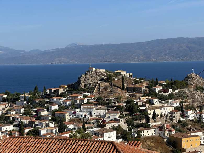 The view of homes in Hydra, with mainland Greece (and its windmills) on the other side of the sea.