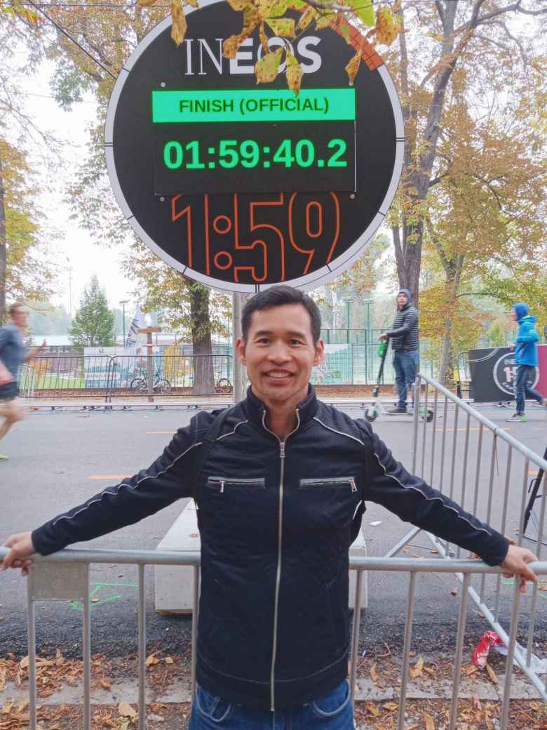 Felix Wong in front of a time clock displaying Eliud Kipchoge's time of 1:59:40. Nowadays I am happy to run 15 miles in that time. Kipchoge ran a whole marathon!