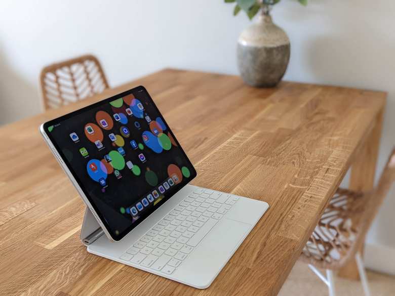 A white silver fifth-generation Apple iPad Pro 12.9 tablet with white Magic Keyboard on a table.