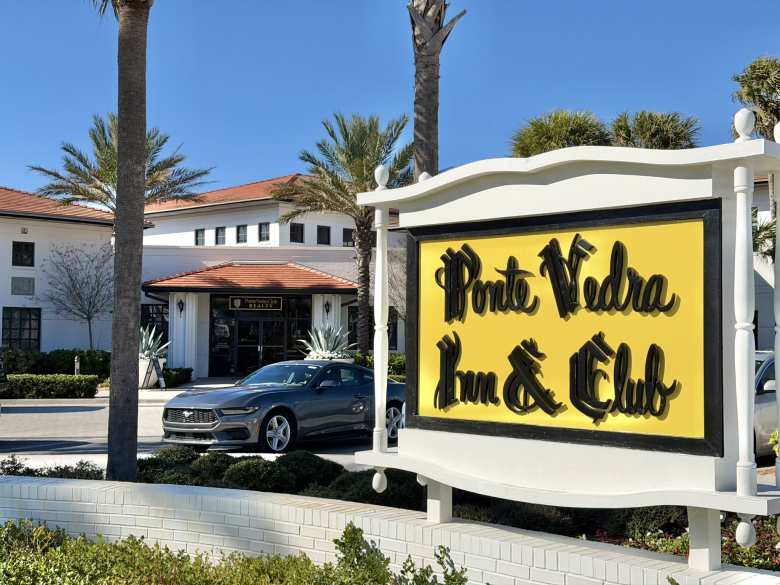 A Carbonized Gray Metallic 2025 Ford Mustang next to a yellow sign that says Ponte Vedra Inn &amp; Club.