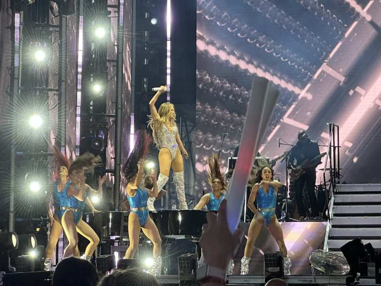 Jennifer Lopez singing on top of a grand piano.