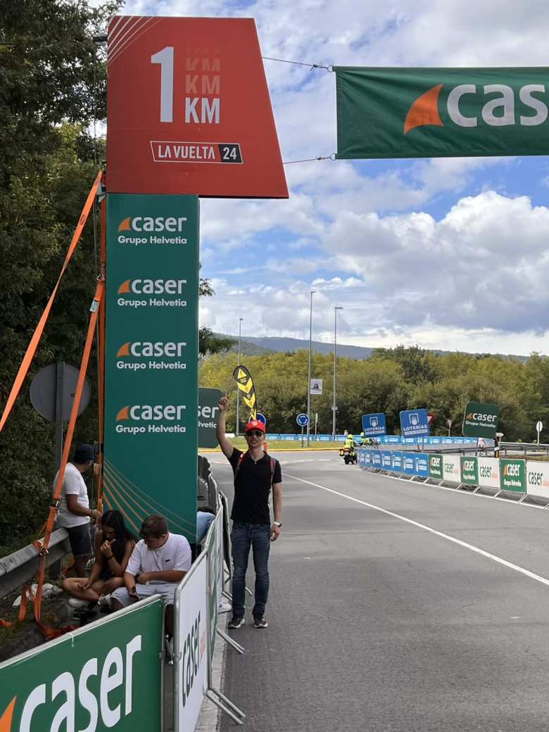 Felix standing underneath the 1 KM to go banner for Stage 11 of La Vuelta in Padrón.