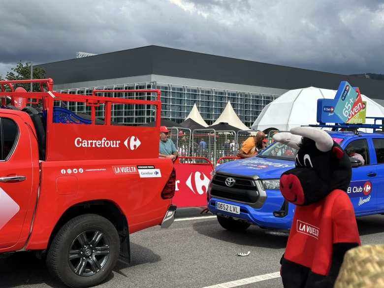 The La Vuelta bull mascot next to a red Carrefour truck.