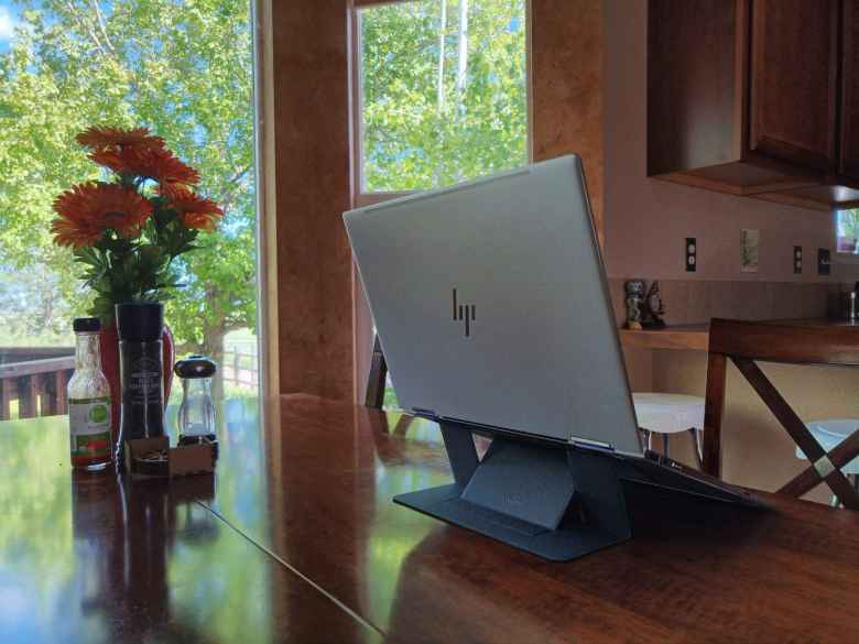 silver HP Spectre x360, black MOFT invisible laptop stand, table by windows