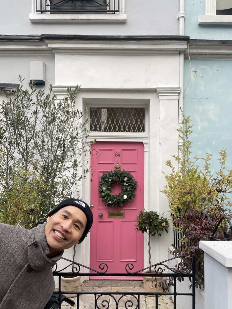 Felix in front of a pink door with a wreath in Notting Hill.