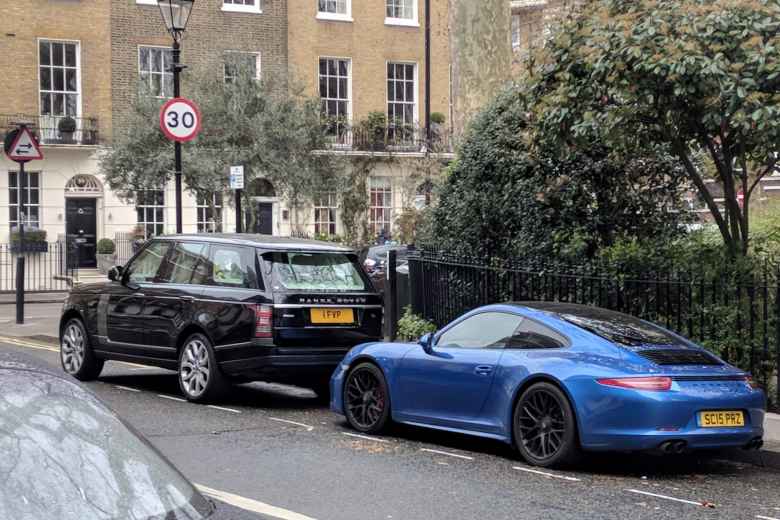 A black Land Rover Discovery and Blue Porsche 911 in a neighborhood north of Hyde Park.