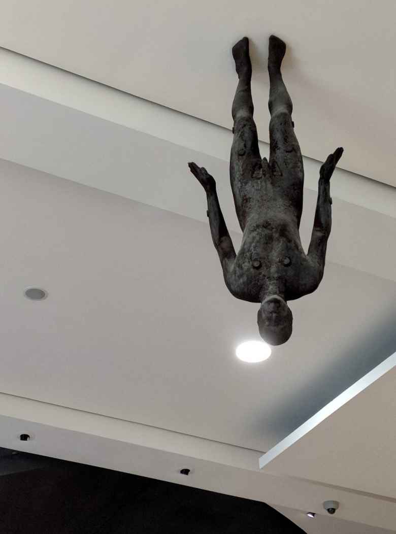 A sculpture of an upside-down man inside the Wellcome Collection in London.