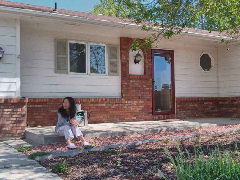 Lina in front of her house and her cat Mulan behind a storm door.