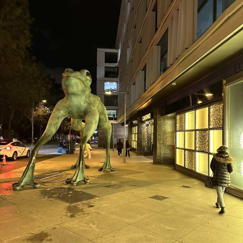 Andrea walking towards a giant frog sculpture in front of a casino near Madrid's Plaza de Colón.
