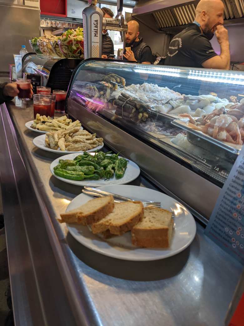 Red wine, sangria, french fries, anchovies (boquerones), peppers (some hot, some not), and bread inside the Mercado Central de Atarazanas.