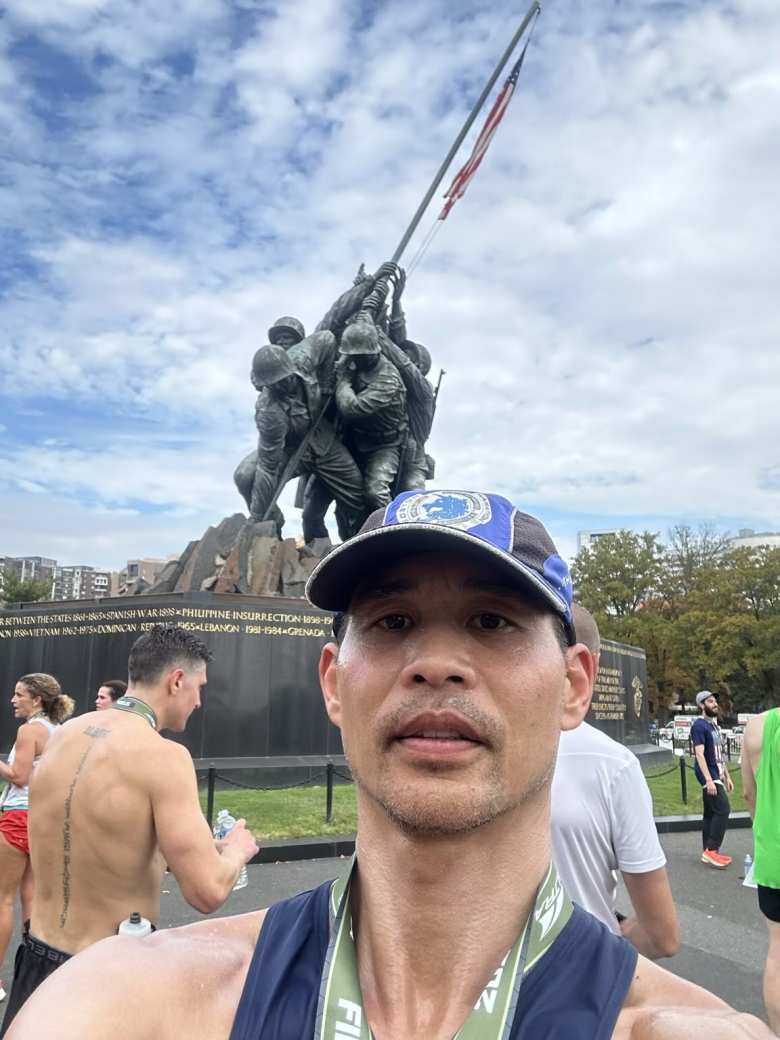 Felix wearing a Marine Corps Marathon finisher's medal in front of the US Marine Corps War Memorial.