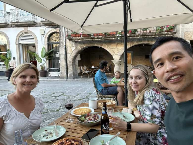 Mel, Andrea, and Felix eating dinner consisting of Spanish tortilla, bread, and salad at Kamelia Taberna in Pontevedra.