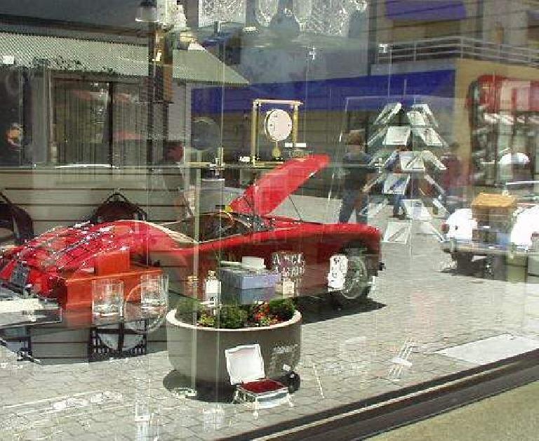 Reflection of a red MGA on the glass windows of a boutique store.