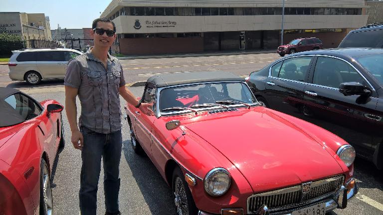 Felix Wong in front of Jennifer Orum's red 1970 MGB roadster.