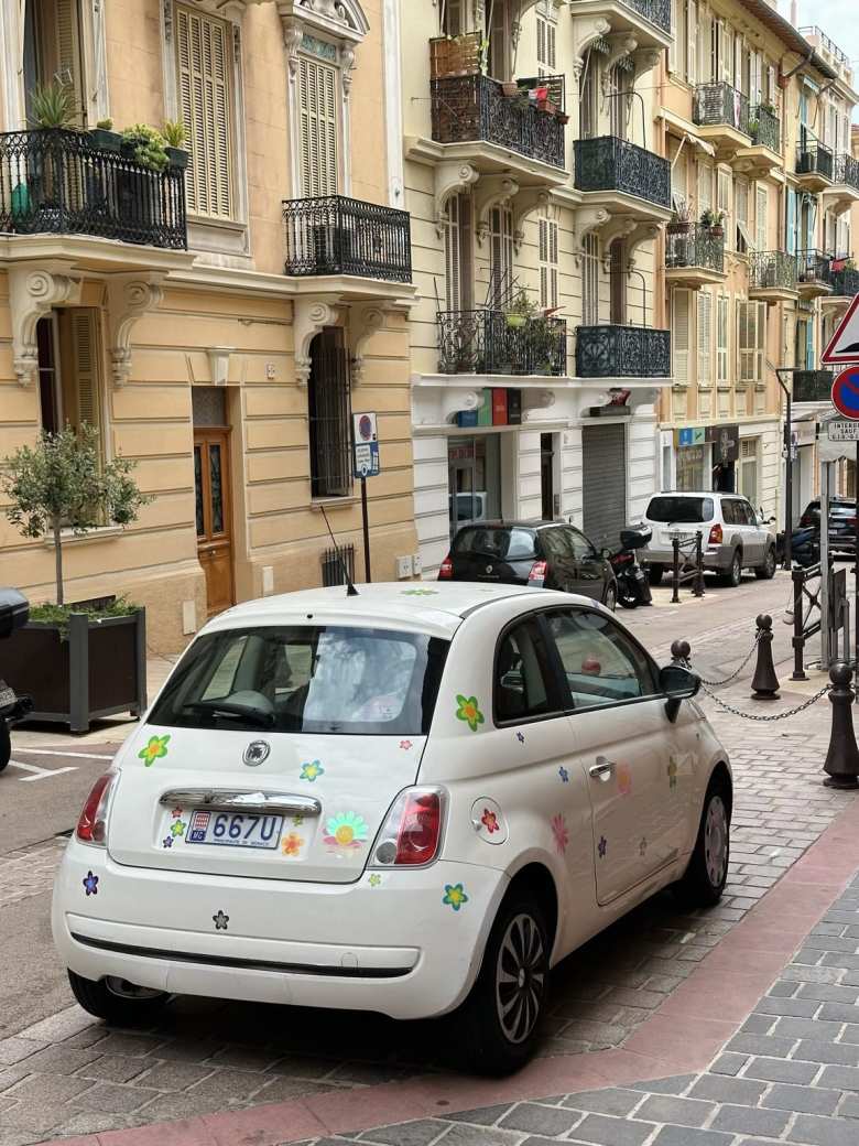 A white FIAT 500 adorned with flowers decals in Monaco.